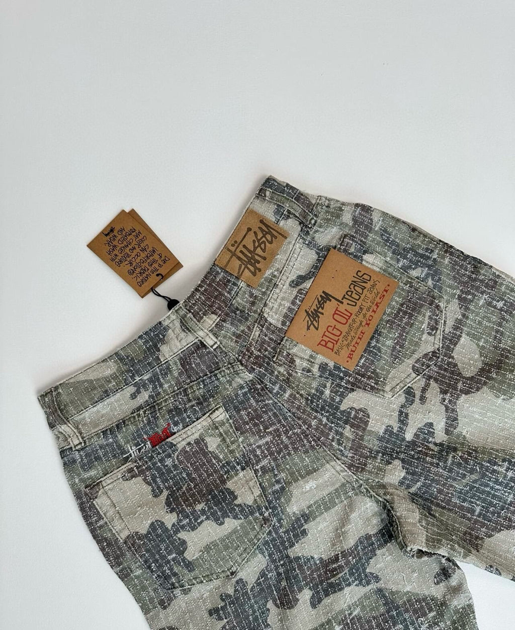 Jean Stüssy SS24 Dro - Coupe droite délavée, orné de broderies cloutées, unisexe, motif camouflage forêt.